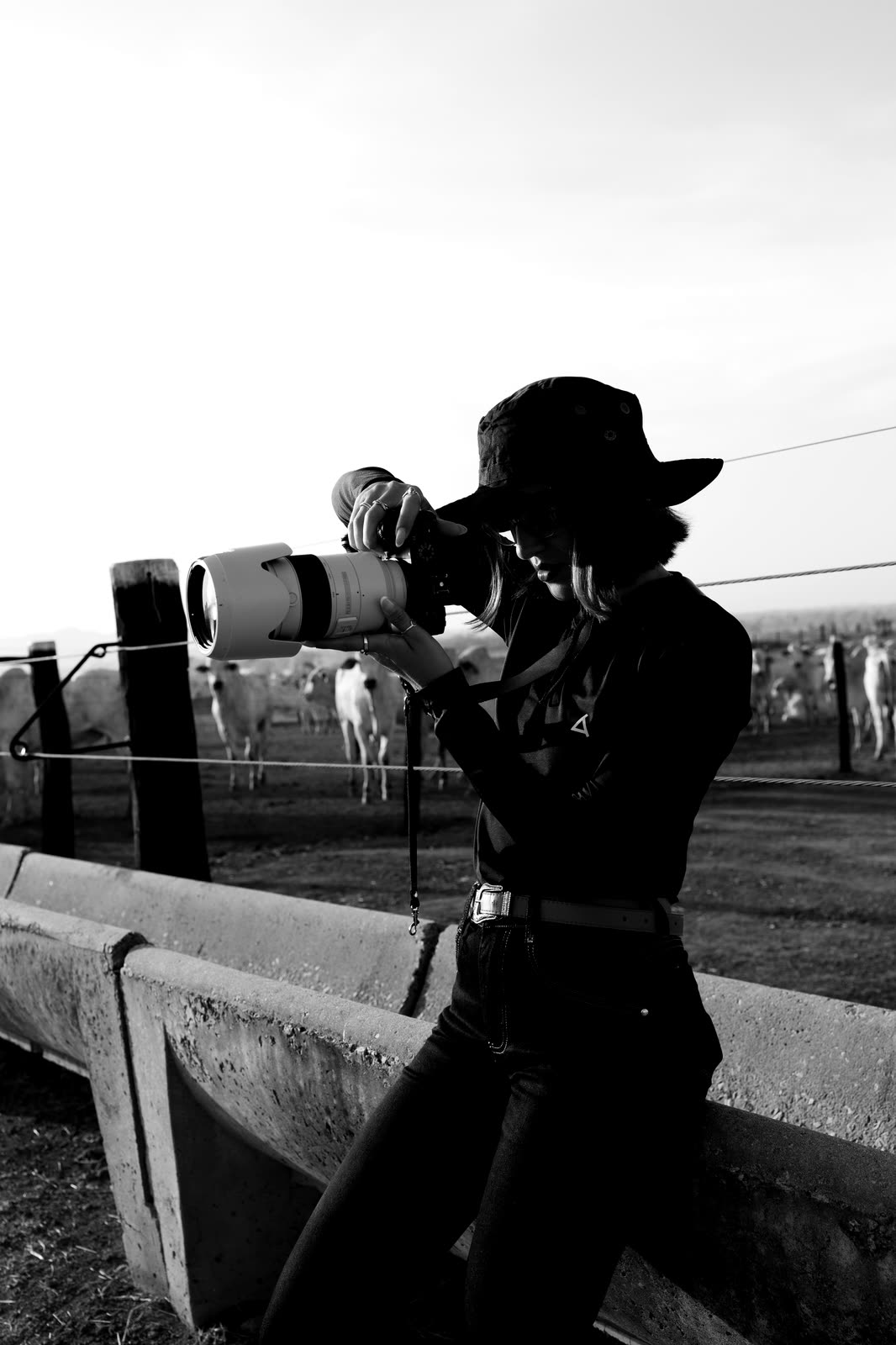 Karine fotografando com teleobjetiva, apoiada numa cerca no Pará
